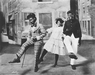 George Walker, Adah Overton Walker (also billed as Aida Overrton Walker) and Bert Williams link arms and dance the cakewalk in In Dahomey. (Wikimedia Commons)